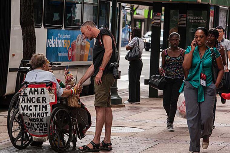 Willie Baronet, a Texas-based artist, speaks with Jim Thomas on Philadelphia's Market Street about the handmade sign Thomas uses to ask for help. July 28, 2014, Philadelphia, Pennsylvania. ( MATTHEW HALL / Staff Photographer )