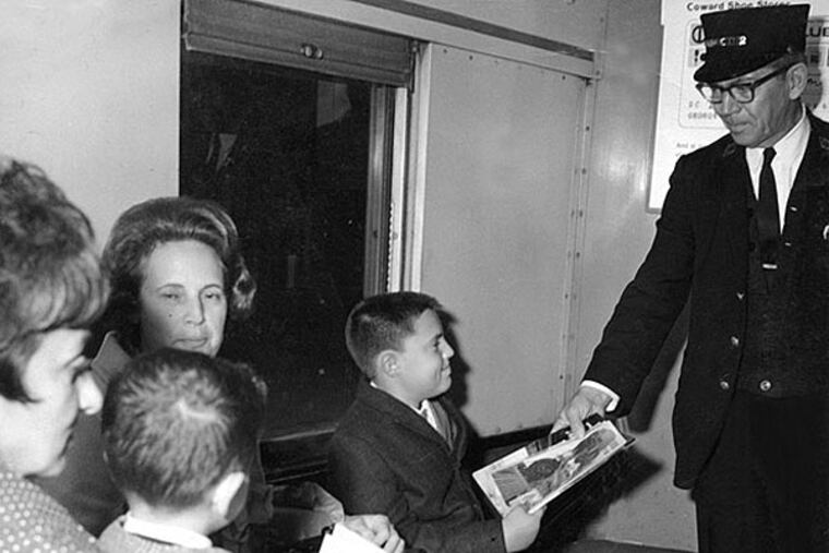 Joseph McKelvie gives a railroad comic book to young Reading rider Frank La Preziosa of Jenkintown.