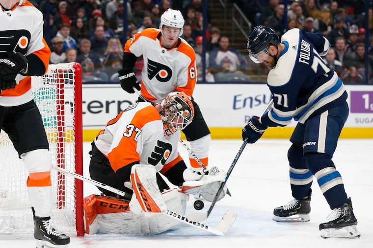 Flyers goalie Brian Elliott (37), left, makes a save against Columbus Blue Jackets' Nick Foligno, right, as Travis Sanheim waits for the rebound during the second period of an NHL hockey game Thursday, Feb. 20, 2020, in Columbus, Ohio.