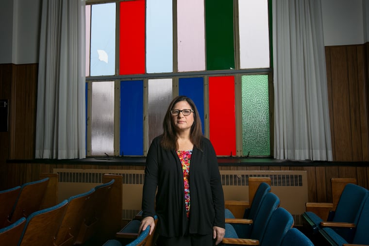 Rabbi Robyn Frisch shown here in front of two of the broken window panes at Temple Menorah Keneseth Chai, on Tuesday in Philadelphia.