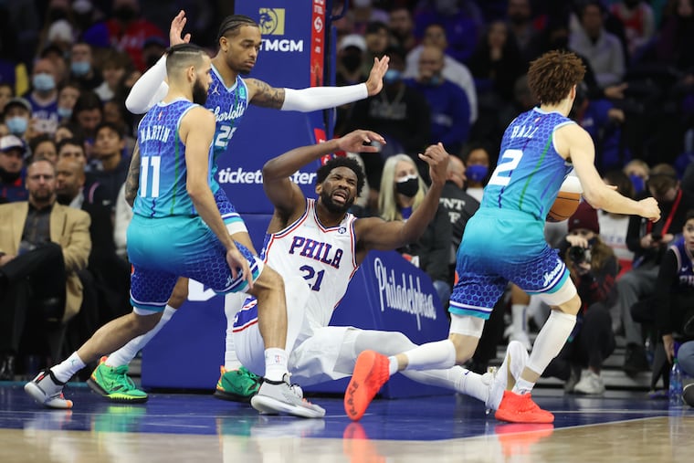 Joel Embiid, center, of the Sixers loses the ball as he is swarmed by (L-R) Cody Martin, P.J.Washington, and LaMelo Ball of the Hornets during the 2nd half of their game at the Wells Fargo Center on Jan. 12, 2022.