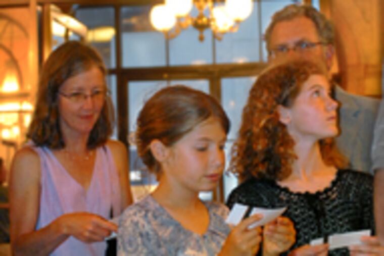 Sisters Eleanor and Anna Wing (right) check their "Wicked" tickets in the Academy lobby. Behind them are their parents, Karen and Scott. The family came to Philadelphia from State College to catch the performance Friday night.