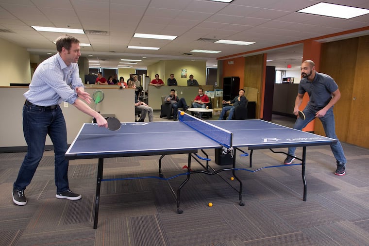 Brian Fenn (left) takes on Ryan Morris in a Friday afternoon game of ping-pong at Advanceon in Exton. Fenn, vice president of operations, admits he isn’t the most skilled member of his tourney team.