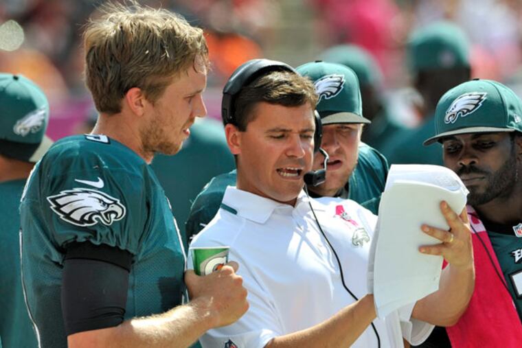 Eagles quarterbacks coach Bill Lazor, center, talks to quarterback Nick Foles, Matt Barkley and Michael Vick. (Steve Nesius/AP)