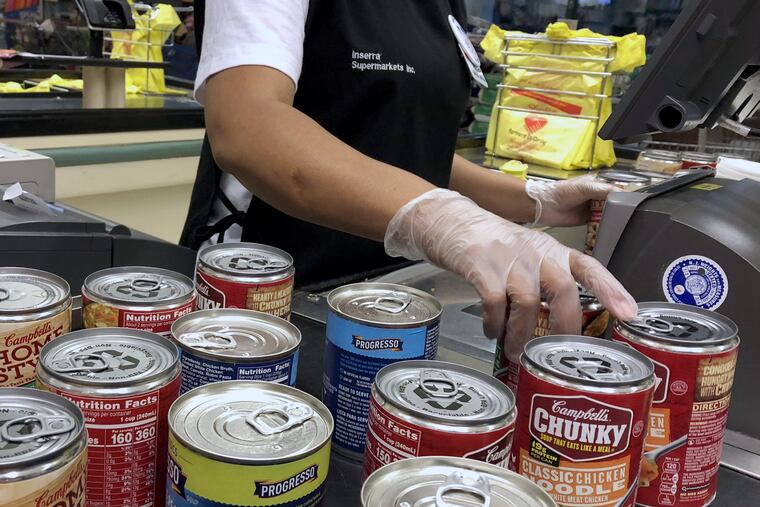 A woman scans the prices on cans of soup into a cash register at a grocery store in North Bergen, N.J.