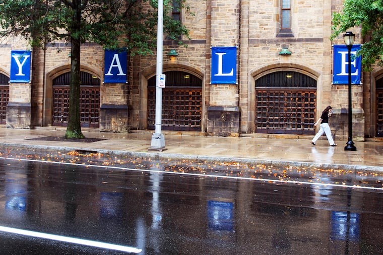 A passerby strolls under a Yale University sign on campus in New Haven, Conn. in 2021.
