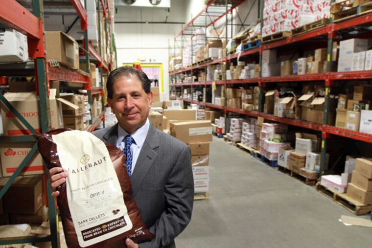 BK Specialty Foods' Kratchman holds a bag of Callebaut Belgian chocolate in his Swedeboro warehouse Tuesday October 29, 2013. BK Specialty Foods, started by Kratchman 27 years ago as a juicing company making deliveries by bicycle, has a far bigger footprint in the food business. (DAVID SWANSON/Staff Photographer)