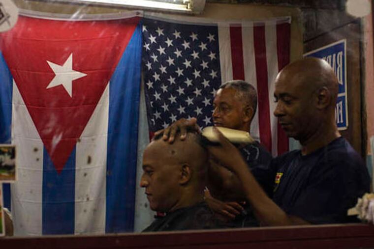 Cuban and U.S. flags hang in Eugenio Lafargue's Havana barbershop. Who isn't so happy? Foreigners, who have had Cuba to themselves. AP