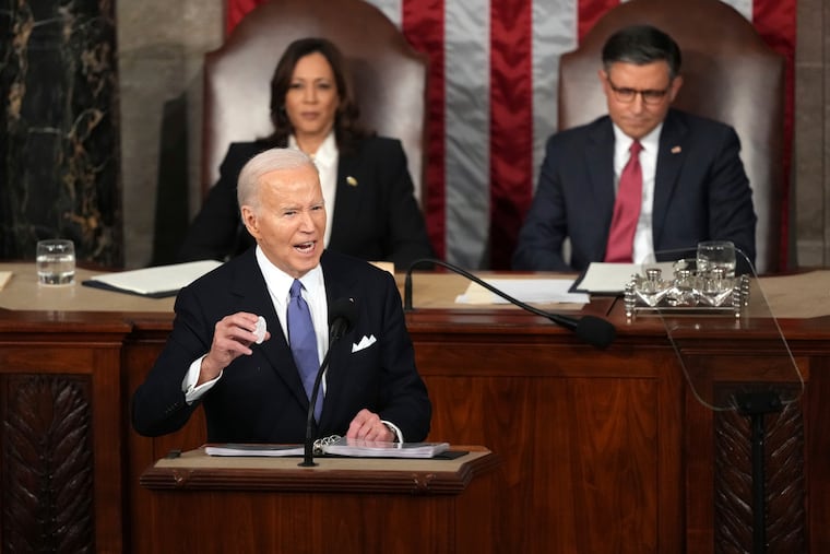 President Joe Biden holds a Laken Riley button as he delivers the State of the Union address to a joint session of Congress at the U.S. Capitol on Thursday, while Vice President Kamala Harris and House Speaker Mike Johnson watch.