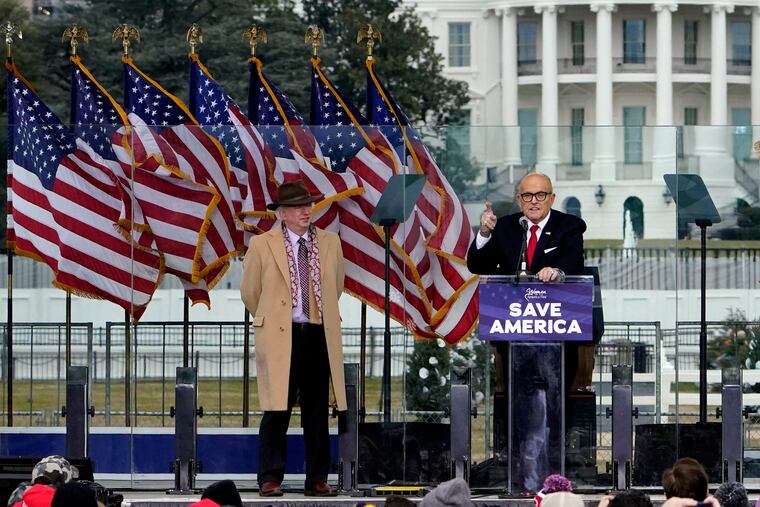 Chapman University law professor John Eastman stands at left as former New York Mayor Rudolph Giuliani speaks in Washington at a rally in support of President Donald Trump, called the "Save America Rally" in 2021.