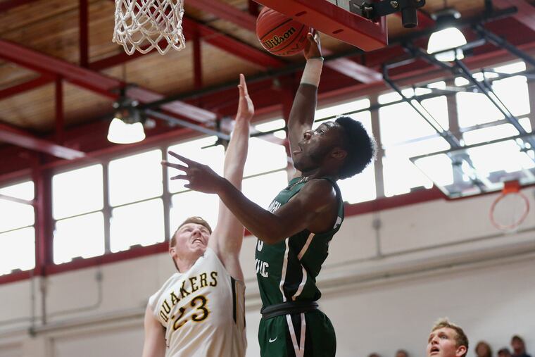 Camden Catholic's Baba Ajike (25) goes up for a dunk past Moorestown's Ben Cantwell (23) during Saturdyay's game at Rancocas Valley.