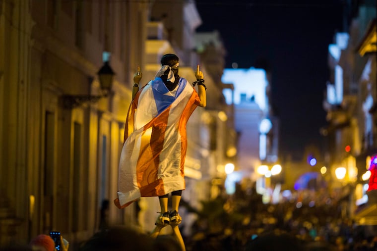 A demonstrator with a Puerto Rican flag reacts during clashes in San Juan, Puerto Rico, Wednesday, July 17, 2019. Thousands of people marched to the governor's residence in San Juan on Wednesday chanting demands for Gov. Ricardo Rossello to resign after the leak of online chats that show him making misogynistic slurs and mocking his constituents.