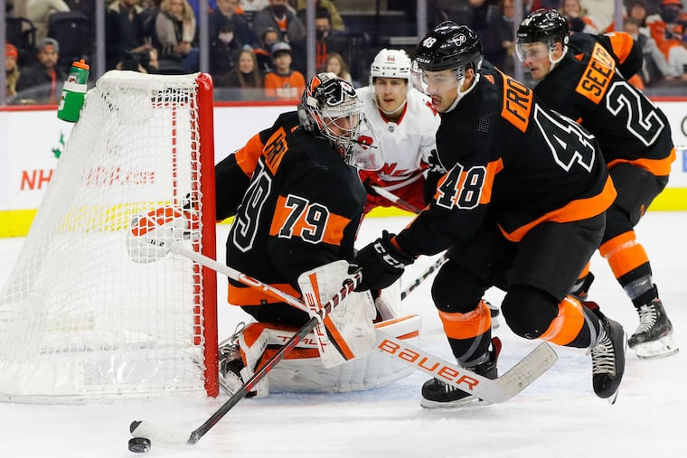 Flyers center Morgan Frost moves to clear the puck away from goaltender Carter Hart during the first period of the team's 6-3 loss to Carolina on Friday.