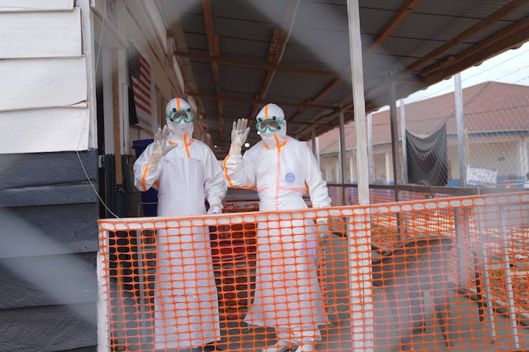 Health workers in protective gear wave inside an Ebola treatment centre in Bunia, Congo, Monday, Aug. 10, 2026.