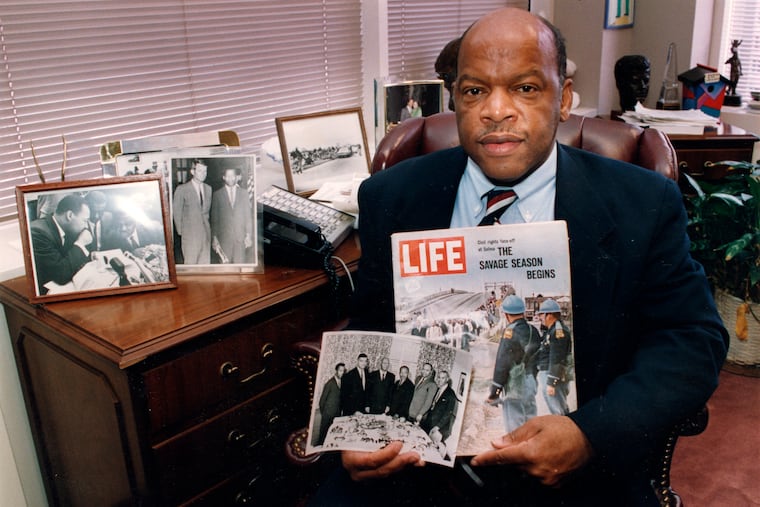 Congressman John Lewis is seen in his Atlanta office with two of his favorite items from his collection of memorabilia from his younger days as a civil rights activist in the 1960s. He is holding a Life Magazine cover picturing the famous Selma march in 1965. (He is in this photo at front of the line of marchers.) He is also holding a photo of the 'Big Six' civil rights leaders of the time to plan for the famous March on Washington. The men in the photo are L to R: John Lewis, Whitney Young, A. Phillip Randolph, Martin Luther King, James Farmer, and Roy Wilkins. In background photos (picture at left) of Dr. Martin Luther King with Fred Shuttlesworth and Ralph Abernathy and Lewis with Robert Kennedy (picture at right)."