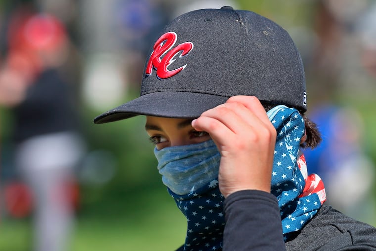 St. Louis RiverCats youth baseball player Carter Herrin, 13, from House Springs, Mo., wears a face covering during the Mother's Day Classic baseball tournament organized by GameTime Tournaments in Cottleville, Mo.. "His mom sent it with him," said Carter's dad ,Noah Herrin. Only a few players and coaches wore masks or face coverings during the tournament.