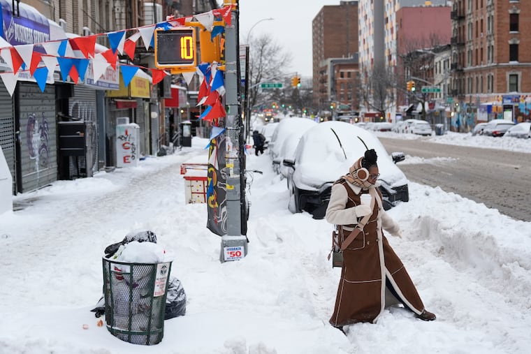 Carrie Hampton tries to navigate a snowy intersection without spilling her coffee in New York, Monday, Jan. 26, 2026.