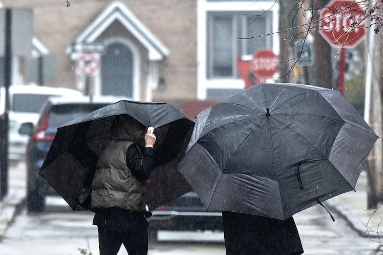 Pedestrians shield themselves from the rain with umbrellas on Monday.