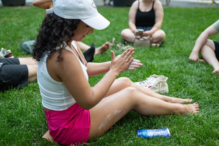 Denise Montan of South Philadelphia applies sunscreen on at City Hall in June. a growing anti-sunscreen movement has taken hold on social media, causing confusion about its benefits and alarming public health experts.