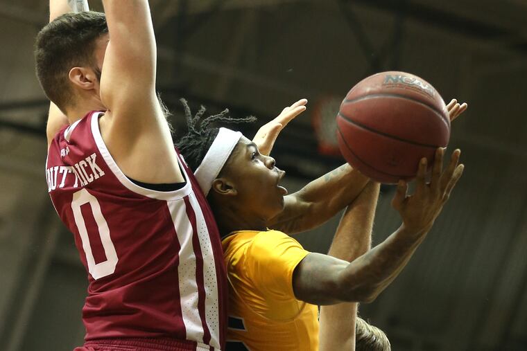 Khalil Brantley, center, of La Salle goes up for a shot between Trent Buttrick, left, and Rich Kelly of UMass during the 1st half on Jan. 26, 2022.