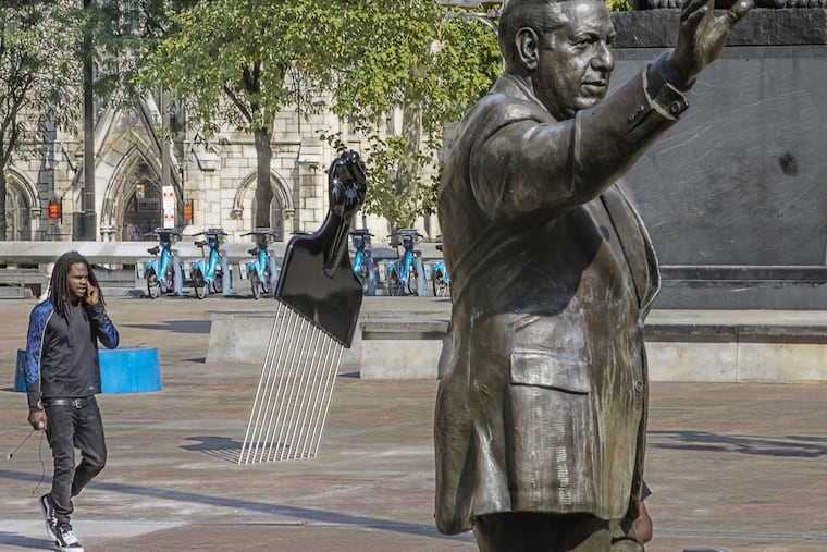 The statue of Frank Rizzo on Thomas Paine Plaza is joined by a new sculpture called “All Power to All People” , a large Afro Pick with a Black Power salute as the handle was installed Tuesday September 12, 2017. The artist is Hank Willis Thomas of New York. On Tuesday at 1:30 The Mural Arts Project will add its own touch to the Rizzo statue saga with the installation a 12-foot high Afro Pick near the Rizzo statue. The Pop Art object inspired by Claes Oldenburg's Clothespin has a Black Power Fist as its handle. The temporary installation by artist Hank Willis Thomas is the first salvo of Monument Lab a public art project kicking off Wednesday. Tuesday September 12, 2017 MICHAEL BRYANT / Staff Photographer
