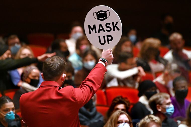 An usher holds up a reminder for the audience to mask up before a Philadelphia Orchestra concert in Verizon Hall in January.