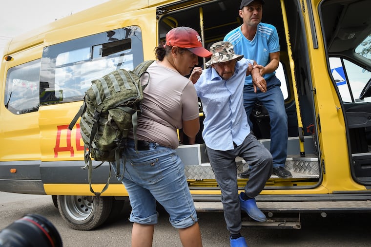 People help evacuate an elderly man from an area near the site of explosion at an ammunition storage site for the Russian army near the village of Mayskoye, in Crimea, on Tuesday.
