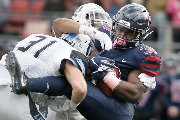 Penn's Karekin Brooks (right) is brought down by Columbia's Ryan Gilbert (31) in 2018. Penn won the game, 13-10.