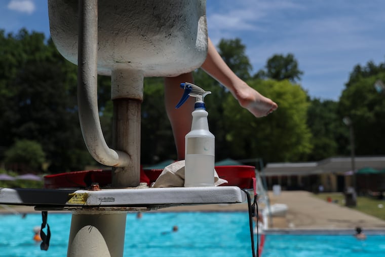 Disinfectant spray sits behind a lifeguard on duty at the St. Albans Swim & Tennis Club in Newtown Square, PA on Wednesday, June 24, 2020.