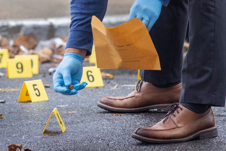 A detective picking up fired cartridge casings in West Philadelphia.
