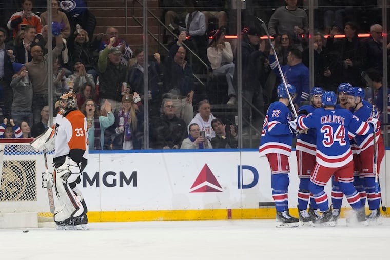 Flyers goaltender Samuel Ersson (left) looks away as the New York Rangers celebrate a goal by Braden Schneider during the first period.