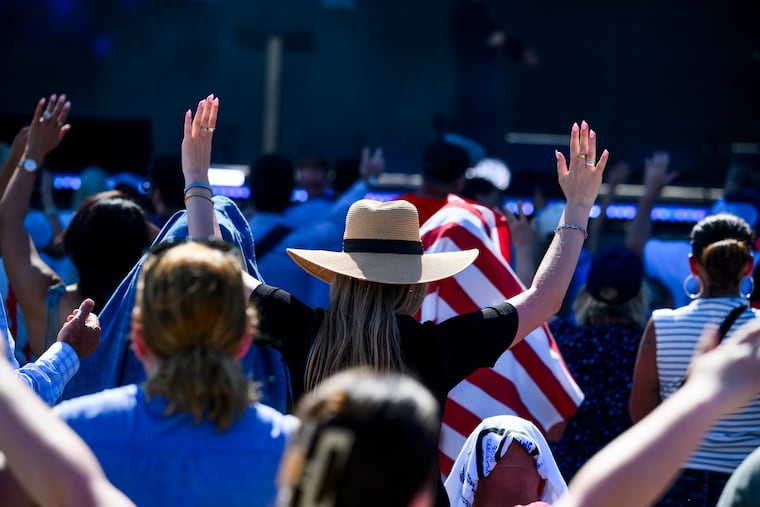 People raise their hands in prayer during an event on the National Mall in May.