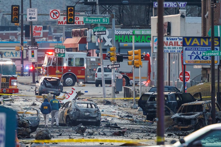 NTSB officials walk through debris from a medical jet crash along Cottman Avenue near Roosevelt Boulevard Saturday.