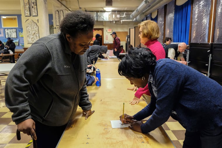 Dee McDowell (left), who is experiencing homelessness, collects her mail from volunteer Chris Martin at Broad Street Ministry on Avenue of the Arts.