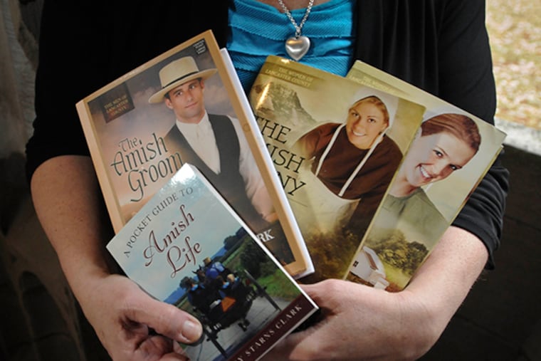 Mindy Starns Clark, a Montgomery County writer, has carved out an interesting niche: Bonnet fiction, or novels about Amish romance. Here, she holds a few of her novels. (Ron Tarver / Staff Photographer)