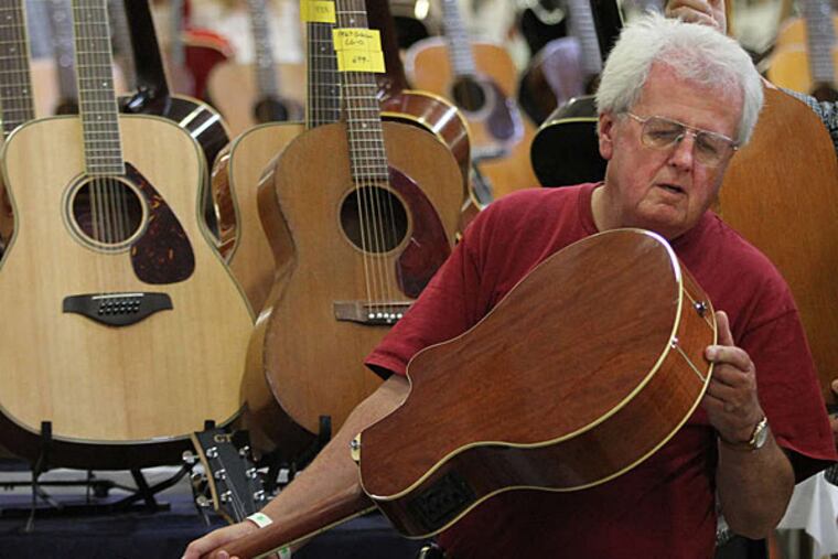Michael Halloran looks over a Yamaha acoustic at the Great American Guitar Show in Oaks on Sunday. (Michael Bryant/Staff)