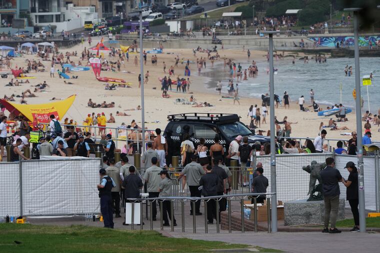 Security officers gather near a gate at Bondi Beach in Sydney, Sunday, Dec. 21, 2025, ahead of a ceremony to mark the National Day of Reflection for victims and survivors from the Bondi shooting on Dec. 14.
