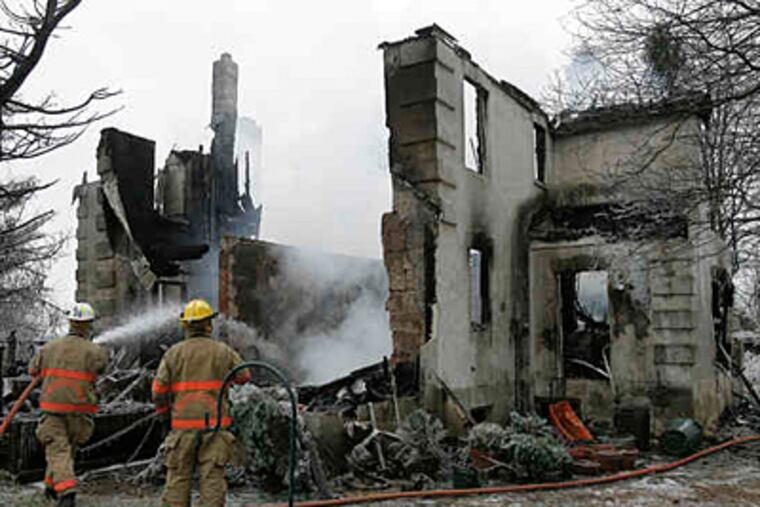 Firefighters hose the still smoldering remains of state Sen. Stewart Greenleaf's Huntingdon Valley house yesterday. (Akira Suwa / Staff)