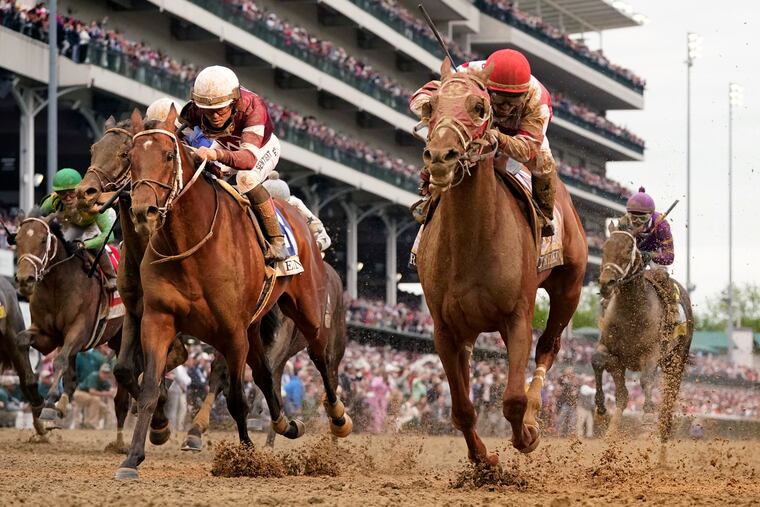 Sonny Leon rides Rich Strike (right) across the finish line to win the 148th running of the Kentucky Derby at Churchill Downs on May 7.