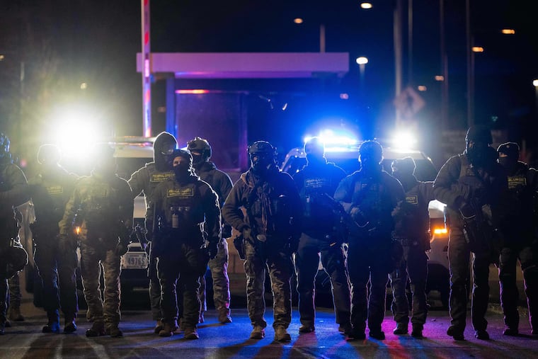 Federal officers stand guard after detaining people outside of Bishop Henry Whipple Federal Building on Tuesday in Minneapolis.