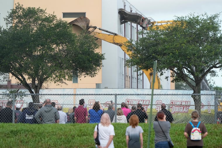 Students, teachers, victims' families and passersby watch June 14 as crews start the demolition of the Marjory Stoneman Douglas High School building where 17 people were killed in the 2018 mass shooting in Parkland, Fla.