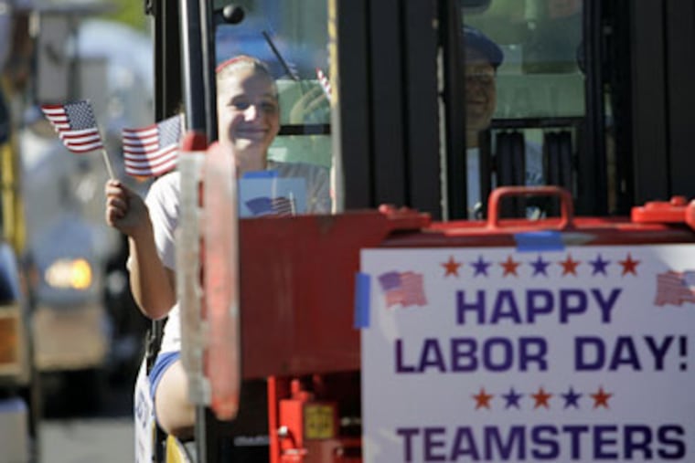 Bernicia Gercio waves her flag as she rides in a fork lift as part of Philadelphia Teamsters Local 830 in the annual Philadelphia Labor Day parade Monday on Columbus Boulevard. (Laurence Kesterson / Inquirer)