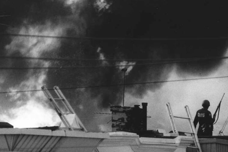 Police on an Osage Avenue roof as the fire rages out of control on May 13, 1985.