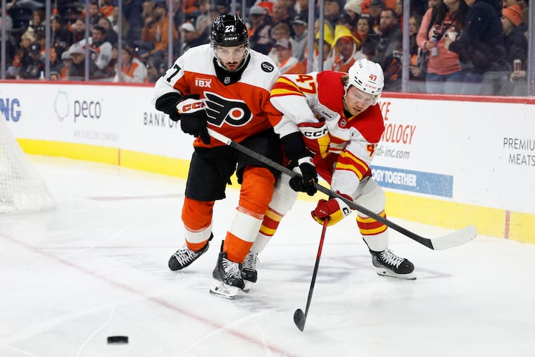 Flyers left wing Noah Cates and Calgary Flames center Connor Zary go after the puck during the second period on Sunday, Nov. 2, 2025 in Philadelphia.