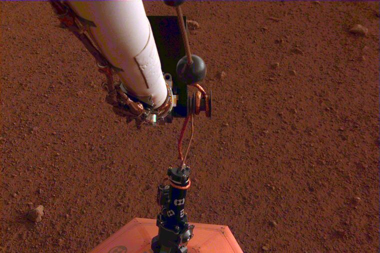 This photo provided by NASA Jet Propulsion Laboratory, shows the new Mars lander placing a quake monitor on the planet’s dusty red surface. The unprecedented milestone occurred less than a month after Mars InSight’s touchdown. InSight’s robotic arm removed the seismometer from the spacecraft deck and set it directly on the ground Wednesday, Dec. 19, 2018 to monitor Mars quakes.(NASA Jet Propulsion Laboratory via AP)
