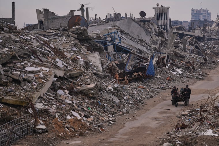 Palestinians pass along a street surrounded by buildings destroyed during Israeli air and ground operations in the Sheikh Radwan neighborhood, in Gaza City, on Tuesday.
