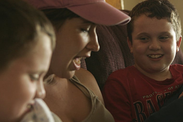 Lindsay Gallagher, a nanny specializing in the care of autistic children, reads a story to the Tuckerman brothers, Tim, left, and Eddie, right. (Michael Perez / Inquirer)
