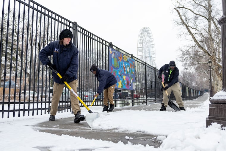 Philadelphia Zoo Garden Service workers Joseph Mineer of Fairmount, Naeem Price of North Philadelphia, and David Wallace of Southwest Philadelphia (from left to right), shovel snow on the sidewalks near the bus drop offs earlier this month. The region is expecting a foot of snow this weekend.