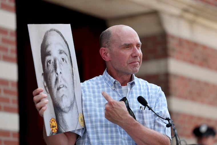 Michael Campana holds up a photo of his father, firefighter Ralph Campana, during a memorial event outside Fireman's Hall Museum in Philadelphia on Sunday, the 50th anniversary of the Gulf Oil refinery fire that killed eight Philadelphia Fire Department firefighters. Campana was one of the eight who died battling the blaze.