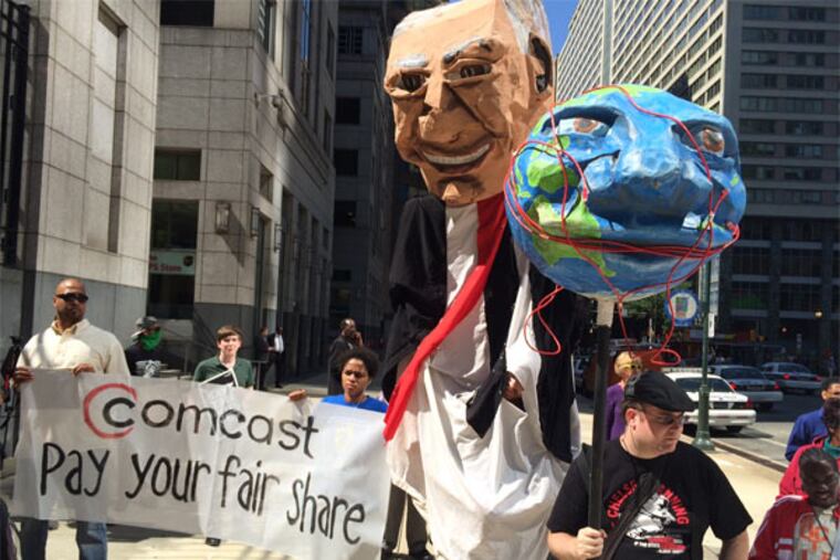 Demonstrators opposed to the merger of Comcast Corp. and Time Warner Cable Inc. and in favor of tighter FCC regulation of the Internet display puppets representing Comcast CEO Brian Roberts and a globe encircled by cable wires. Outside Comcast headquarters in Philadelphia, Sept. 15, 2014. (Bob Fernandez / Staff)